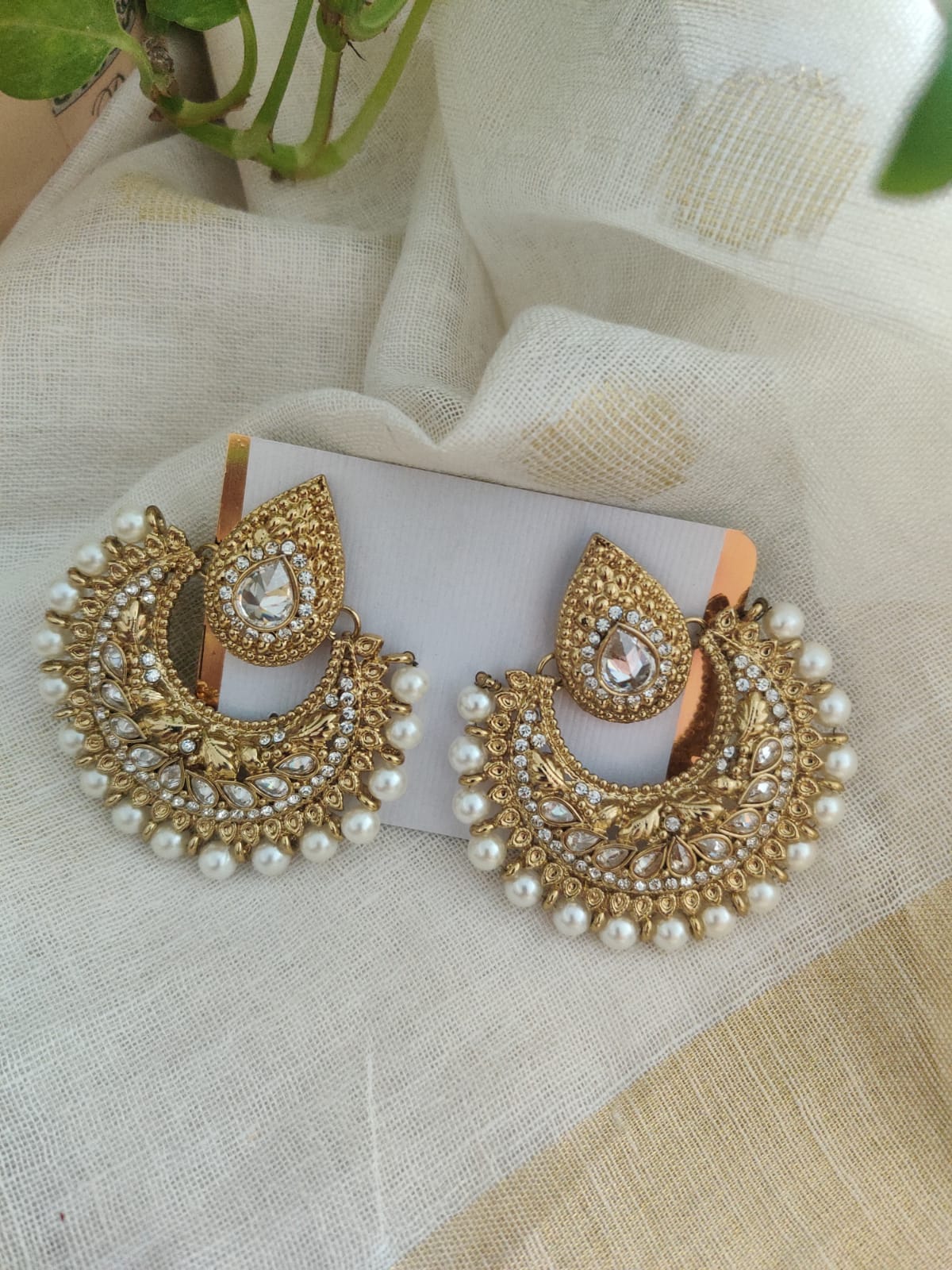 A pair of golden brass earrings with purple stone embedded in the design