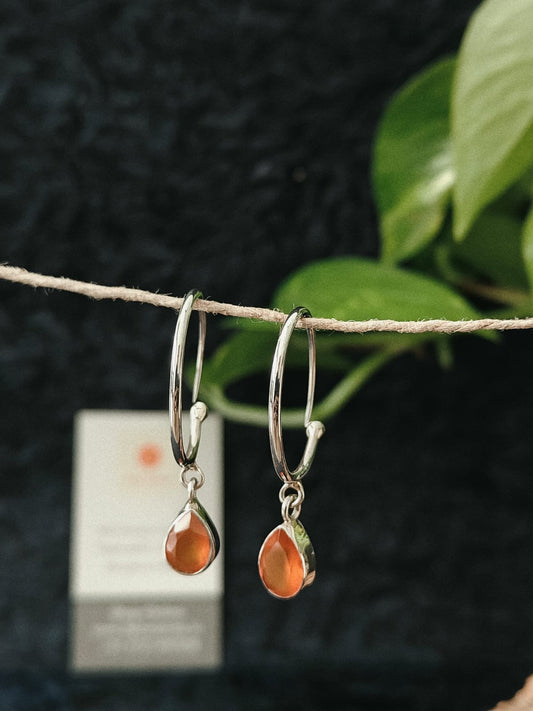 Silver hoop earrings with teardrop-shaped orange gemstones 
